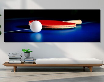 May include: A close-up of a red and black ping pong paddle with a white ball in front of it. The paddle is on a blue table with a dark background.
