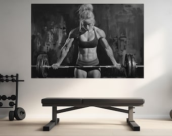 May include: A black and white photograph of a woman lifting a barbell. She is wearing a black sports bra and black shorts. The background is a textured wall.