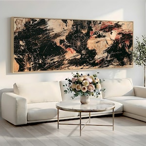May include: A large rectangular wall art piece featuring an abstract world map design in black, beige, and deep red tones with a compass rose detail, framed in light wood, displayed above a white sectional sofa and a round marble coffee table.