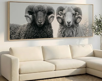 May include: A rectangular wall art piece featuring a black and white photograph of two rams with large curled horns. The ram on the left has dark wool, while the ram on the right has light wool. The artwork is enclosed in a thin wooden frame.