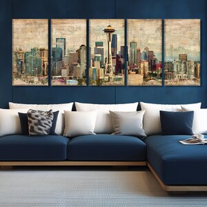 May include: A five-panel wall art set depicting a cityscape with a prominent tower. The artwork features a vintage, textured style with muted colors of beige, blue, and brown. A navy blue sectional sofa with white pillows is in the foreground.