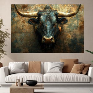 May include: A large canvas print depicting a close-up of a bull's head. The bull has dark fur, large horns, and a textured, aged background with brown, blue, and gold tones. The artwork is displayed above a white sofa in a living room.
