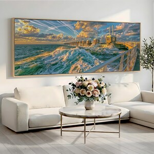 Peut inclure: Une impression d'art mural panoramique représentant une tempête côtière s'écrasant contre une barrière maritime en béton au coucher du soleil. La scène montre des vagues turquoise turbulentes, un ciel doré nuageux et une rambarde métallique.