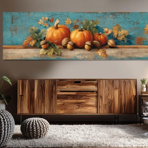 May include: A rectangular canvas print depicting a still life of pumpkins, acorns, and autumn leaves. The pumpkins are orange, the leaves are yellow and brown, and the background is a distressed teal colour. The artwork is a seasonal decoration.