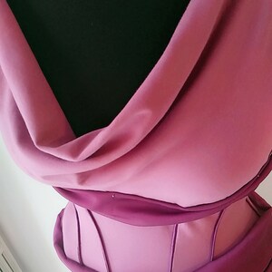 May include: A mauve and dark magenta bodice featuring a draped cowl neckline and a structured midsection with vertical piping details. The garment displays a layered fabric construction with a soft matte finish, showcasing a contrast between the lighter mauve draped upper section and the darker magenta structured waist area.