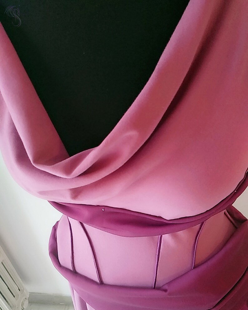 May include: A mauve and dark magenta bodice featuring a draped cowl neckline and a structured midsection with vertical piping details. The garment displays a layered fabric construction with a soft matte finish, showcasing a contrast between the lighter mauve draped upper section and the darker magenta structured waist area.