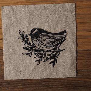 May include: A black and white illustration of a bird perched on a branch with leaves. The bird is facing to the right and has a long tail. The branch is curved and has several leaves.