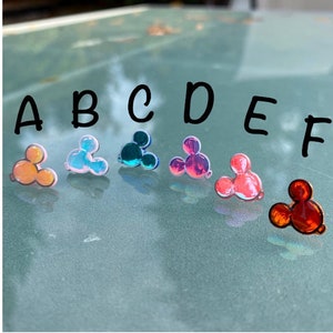 Puede incluir: Seis abalorios iridiscentes en forma de cabeza de Mickey Mouse en diferentes colores: naranja, rosa, azul, morado, rojo y rojo. Los abalorios están etiquetados de la A a la F.