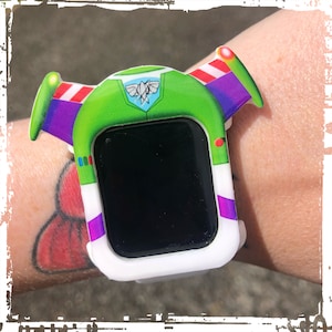 May include: A white Apple Watch with a green, purple, and red  'Toy Story' character watch band. The band features a cartoon image of Buzz Lightyear's helmet and spacesuit.