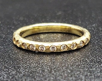 May include: A gold band ring with a hammered texture and a row of small diamonds set in the band.