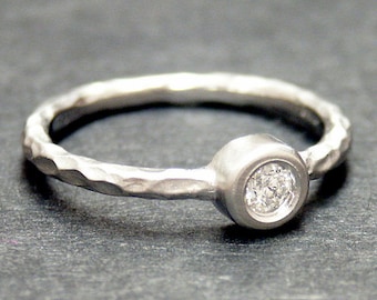 May include: A silver ring with a hammered texture and a bezel-set round diamond.