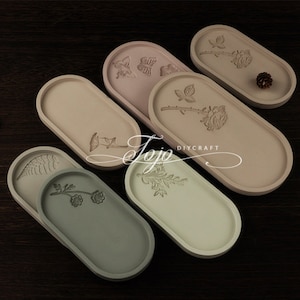 May include: Six oval-shaped concrete trays with different floral designs. The trays are in various shades of beige and green. The text "DIYCRAFT" is visible on one of the trays.