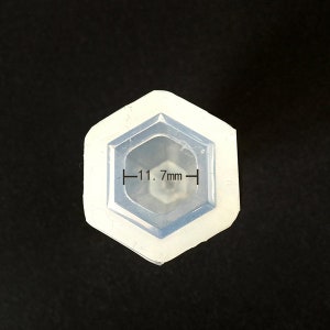 May include: A white silicone mold shaped like a hexagon with a 1.7 inch diameter opening. The mold is designed for making resin crafts.