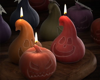 Könnte beinhalten: Ein Set mit sechs Halloween-Kerzen in Kürbisform mit verschiedenen Gesichtsausdrücken. Die Kerzen sind in Orange-, Rot-, Lila-, Grün- und Blautönen gehalten.