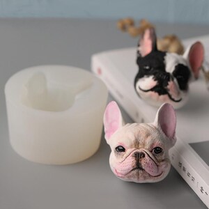 Può includere: Due stampi in silicone per realizzare figurine di bulldog francese. Uno stampo è bianco e l'altro è di colore marrone chiaro. Entrambi gli stampi hanno la forma della testa di un bulldog francese.