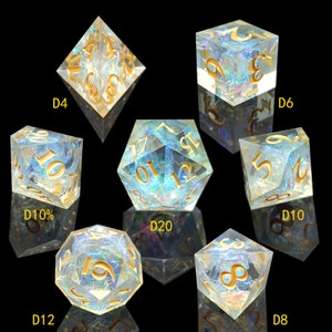 May include: Set of seven iridescent resin dice for tabletop games. Each die features gold-colored numbers and a unique internal design. Includes D4, D6, D8, D10, D10%, D12, and D20 dice.