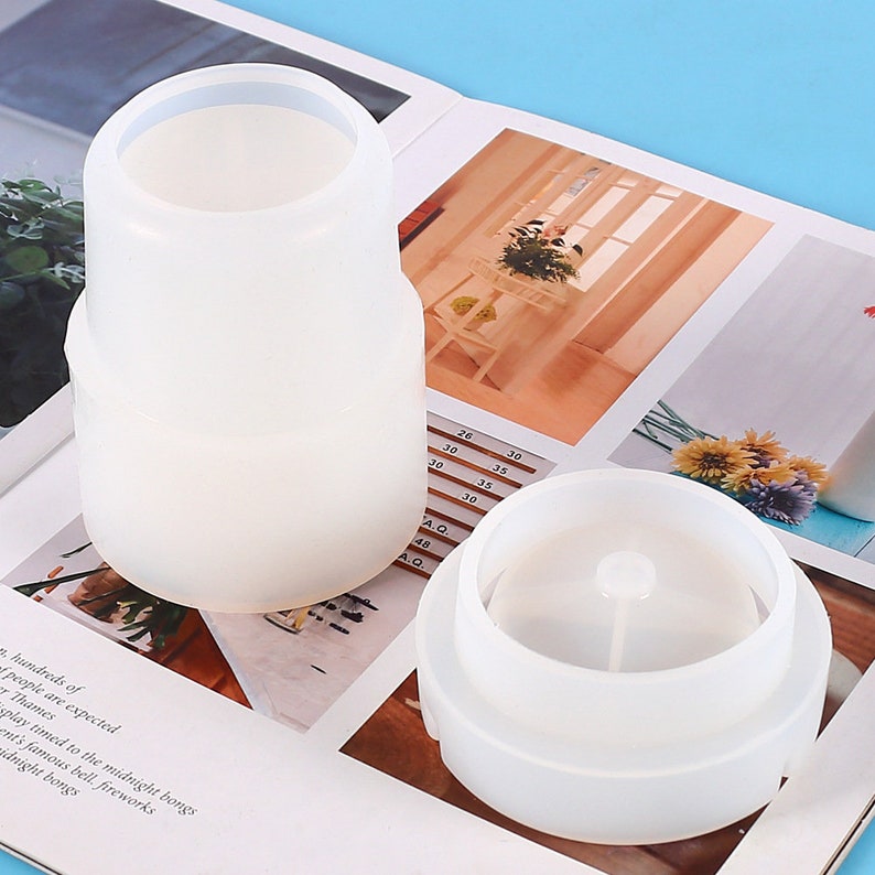 May include: Two white silicone chair leg protectors. The protectors are cylindrical and have a smooth surface. The protectors are stacked on top of each other.
