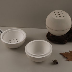 Puede incluir: Tres recipientes de cerámica blanca con tapas. Los recipientes son redondos y tienen un acabado liso y mate. Las tapas tienen pequeños agujeros para la ventilación. Los recipientes están dispuestos sobre una superficie gris claro.