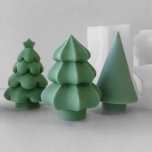 Puede incluir: Tres velas verdes con forma de árbol de Navidad, cada una con un diseño diferente. Las velas están hechas de un material liso y mate y tienen una base ligeramente redondeada.