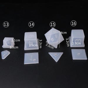 May include: Set of six clear silicone molds for making dice. The molds are numbered 13 through 16 and include a d4, d6, d8, d10, d12, and d20. The molds are 3.2 cm tall and 2.9 cm wide.