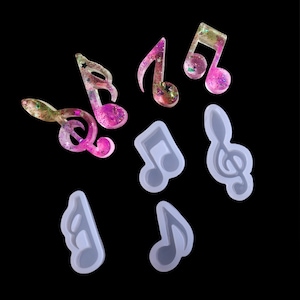 Puede incluir: Un juego de moldes de silicona para hacer manualidades de resina. Los moldes tienen forma de notas musicales, incluyendo una clave de sol. Los moldes son transparentes y tienen una superficie lisa.