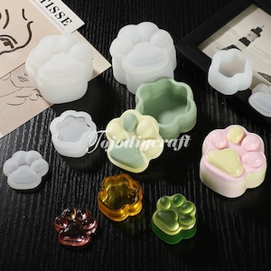 Può includere: Set di stampi in silicone per realizzare oggetti in resina a forma di impronta di zampa. Gli stampi sono mostrati con pezzi di resina finiti in vari colori.
