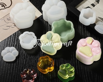 Può includere: Set di stampi in silicone per realizzare oggetti in resina a forma di impronta di zampa. Gli stampi sono mostrati con pezzi di resina finiti in vari colori.