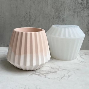 Puede incluir: Dos moldes de maceta de cerámica blanca y rosa con un diseño acanalado. Los moldes están hechos de silicona y son perfectos para crear macetas únicas.