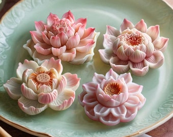 May include: Four pink and white lotus flower shaped decorative items on a green plate.
