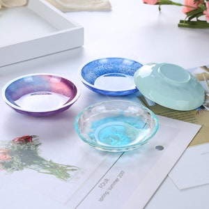 May include: Four small, decorative bowls in different colors. The bowls are made of resin and have a glossy finish. The bowls are perfect for holding small items, such as jewelry or trinkets.