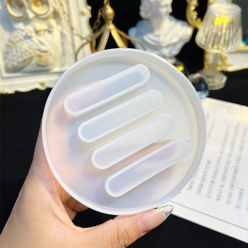 May include: White silicone mold with four rectangular cavities. The mold is round and has a smooth surface.