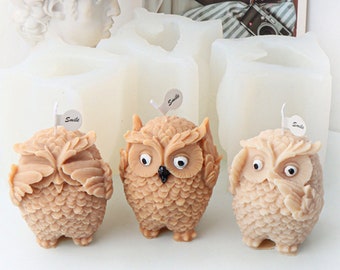 May include: Three brown owl-shaped candles with black eyes and a textured surface. Each candle has a small white tag with the word "Smile" on it.