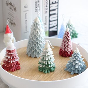 May include: Assortment of six Christmas tree candles in various colors, including red, green, and blue. The candles are arranged on a wooden tray with a white rim.