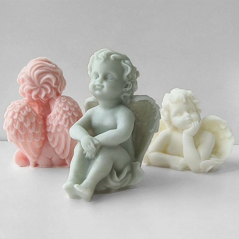 May include: Three small angel figurines made of white and light blue soap. The angels are sitting and have wings.