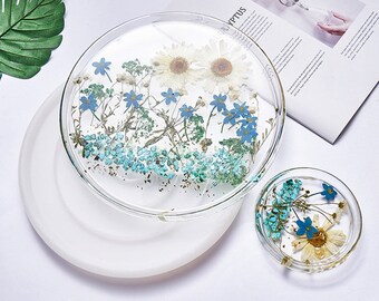 May include: Two clear resin trays with pressed flowers and blue and white flower accents. The larger tray is on a white silicone mold.