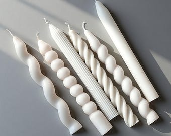May include: A collection of five white taper candles with distinct textures. The set includes a wavy candle, a spherical beaded candle, a vertically ribbed candle, a twisted spiral candle, and a smooth, plain cylindrical taper candle.