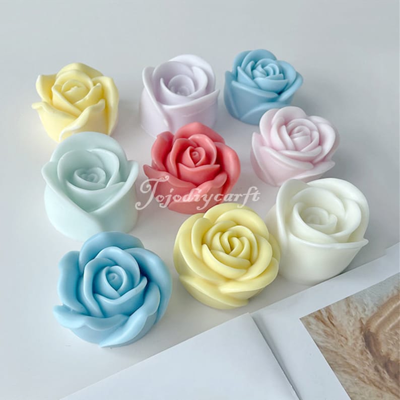 May include: Assortment of ten handmade rose-shaped soaps in various pastel colors, including pink, yellow, blue, and white. The soaps are arranged on a white surface.