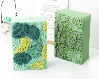 May include: Two green rectangular candles with a leaf design. The candles have a textured surface and are made of a soft, pliable material.