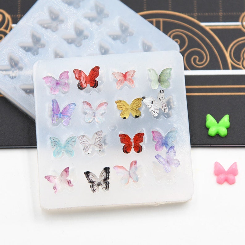 Pu&ograve; includere: Uno stampo in silicone con 16 forme a farfalla. Lo stampo &egrave; trasparente e ha uno sfondo bianco. Le farfalle sono di vari colori, tra cui rosa, blu, verde, giallo, rosso e nero.