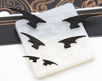 May include: A white silicone mold with six black bat wing shapes. The mold is designed for making resin or polymer clay crafts.