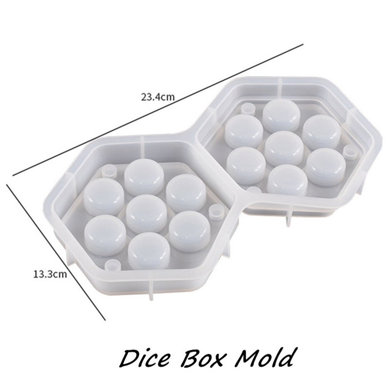 May include: A clear, hexagonal dice box mold with two connected compartments, each holding seven circular impressions. The mold measures 9.2 inches long and 5.2 inches wide. The text "Dice Box Mold" is at the bottom.