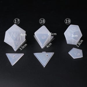 May include: Three clear silicone molds for making dice. The molds are numbered 17, 18, and 19. The molds are different sizes, with the largest mold measuring 3 inches by 1.8 inches. The molds are all shaped like dice, with the numbers 1 through 6 on each side.