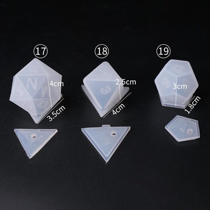 May include: Three clear silicone molds for making dice. The molds are numbered 17, 18, and 19. The molds are different sizes, with the largest mold measuring 3 inches by 1.8 inches. The molds are all shaped like dice, with the numbers 1 through 6 on each side.