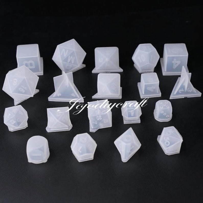 May include: A set of 17 clear silicone molds for making dice. The molds are in various shapes, including a cube, a pyramid, and a dodecahedron. The molds are all made of clear silicone and are designed to be used with resin.