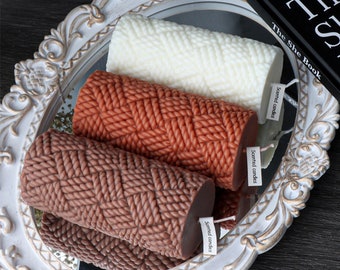 Peut inclure: Trois bougies parfumées dans un plateau décoratif blanc. Les bougies sont en forme de tresse et sont de couleur marron, orange et blanche.