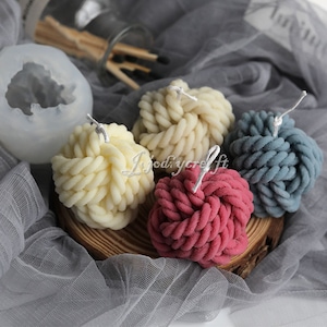 May include: Four decorative candles in the shape of a rope knot. The candles are in the colors white, light blue, and pink.