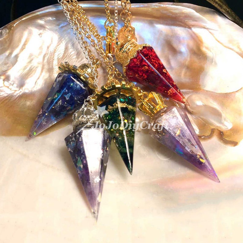 May include: Five gold chain necklaces with different colored crystal point pendants. The pendants are red, green, blue, purple, and a clear iridescent color. The pendants are all in the shape of a point and have gold accents.