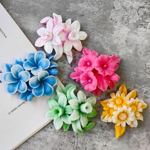 May include: Five different flower-shaped silicone moulds, each with a different colour and design. The moulds are made of a flexible silicone material and are perfect for making fondant flowers, gum paste flowers, or chocolate flowers.