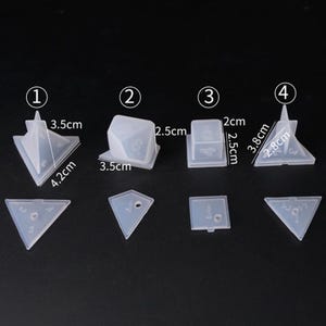 May include: Set of clear plastic molds for making resin dice. The molds are numbered 1 through 4 and include a variety of shapes, including a pyramid, cube, and triangle. The molds are approximately 2.5 cm to 4.2 cm in size.