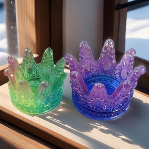 Puede incluir: Dos platos de cristal iridiscente en forma de corona. El plato más grande es morado y azul, el más pequeño es verde y azul.